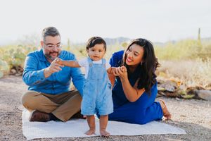 Family lying on white blanket during desert photoshoot with mountains in background.