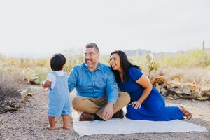 Family relaxes together on white blanket during desert photo session.