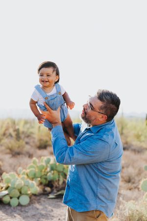 A joyful moment between parent and child playing together in a desert landscape with cacti.