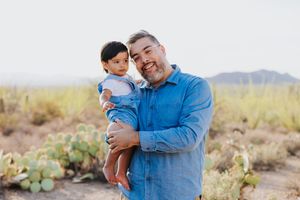 Family portrait in the desert with mountains and cacti in the background.