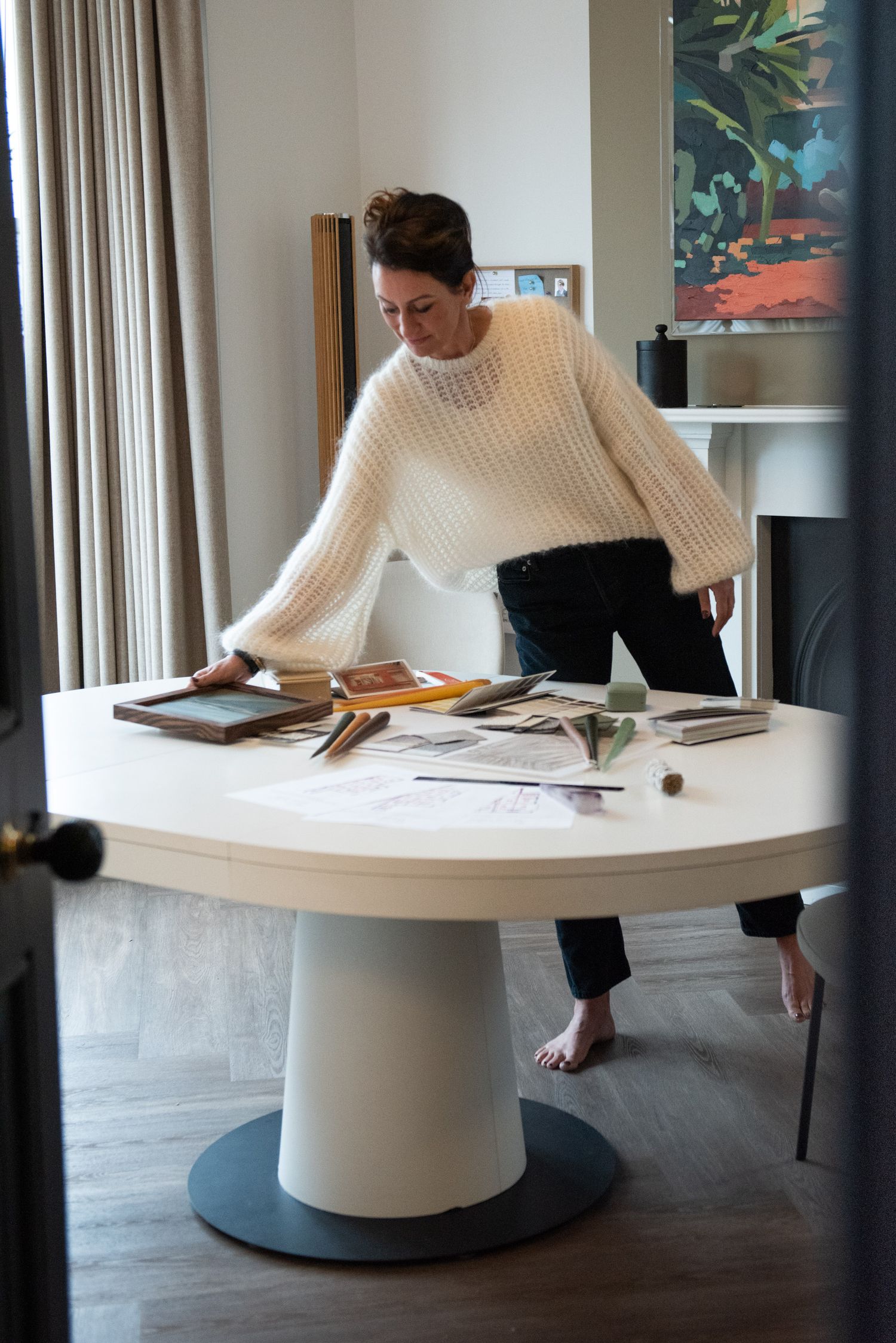 Brand photography - Woman wearing a cream jumper reaching across a table covered in interior design swatches