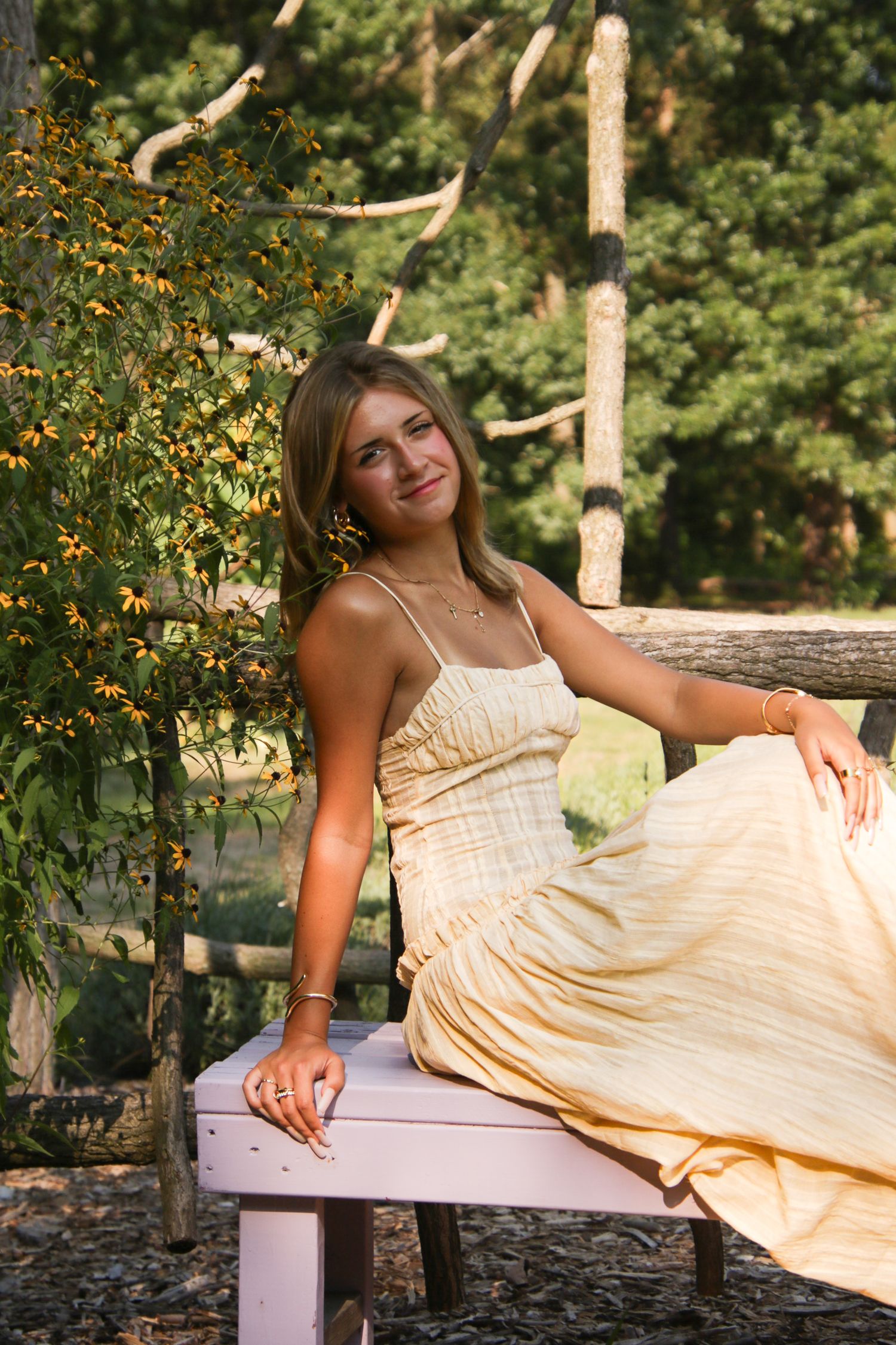Dreamy outdoor portrait session in a park with a flowing cream dress against natural scenery.
