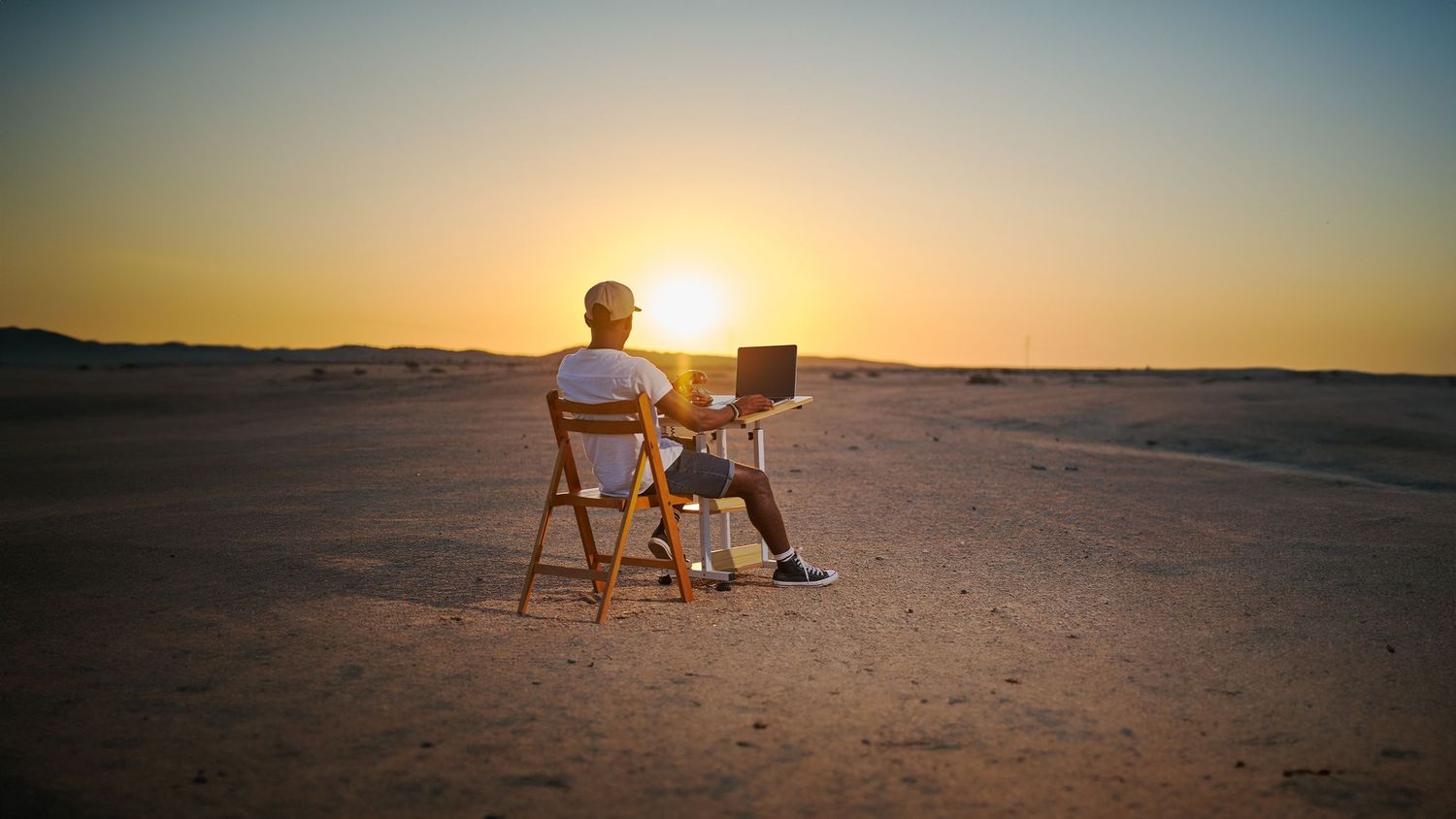A PERSON SEATING ON A CHAIR WATCHING THE SUNSET