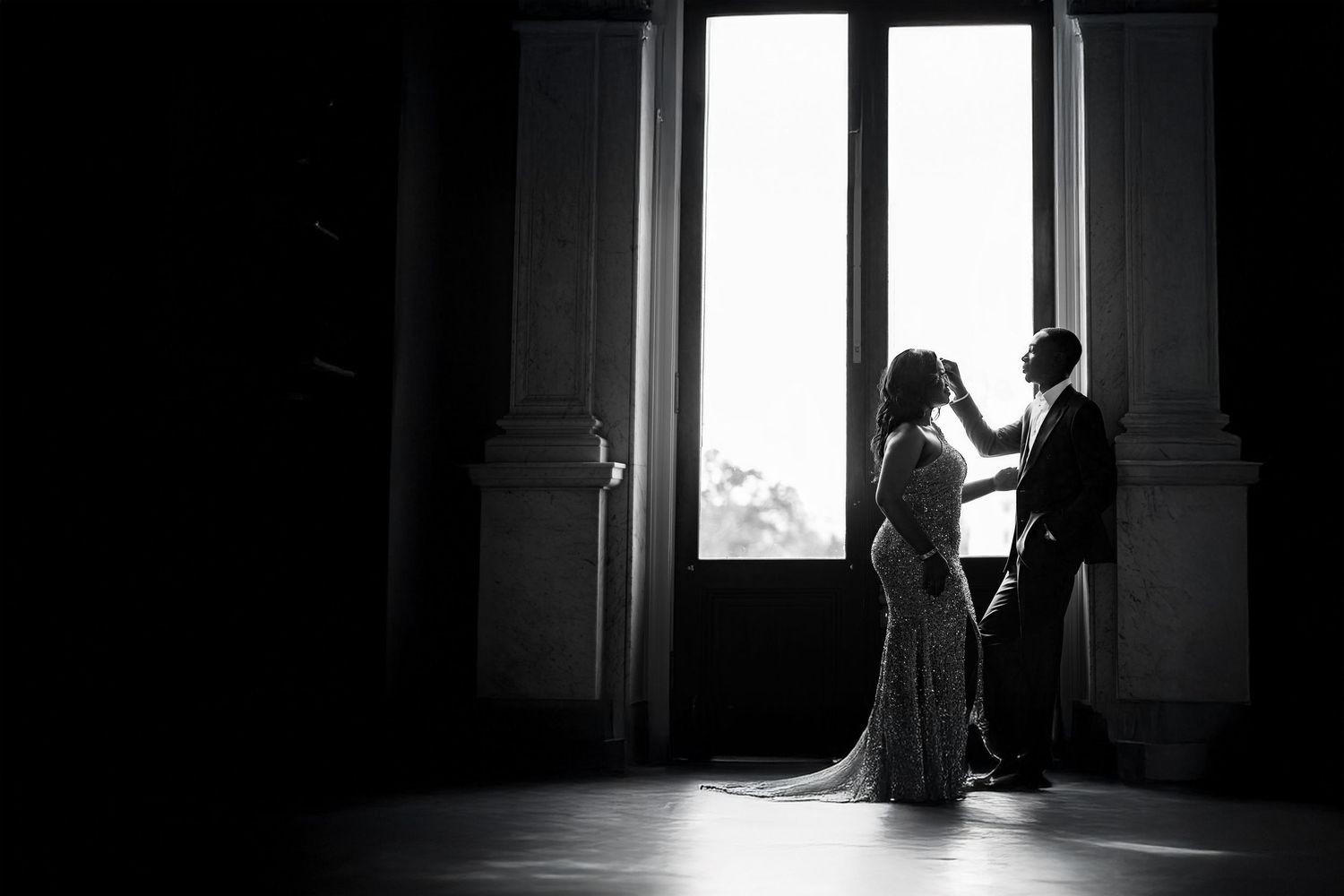 Dramatic black and white photo of light streaming through windows in an empty room.