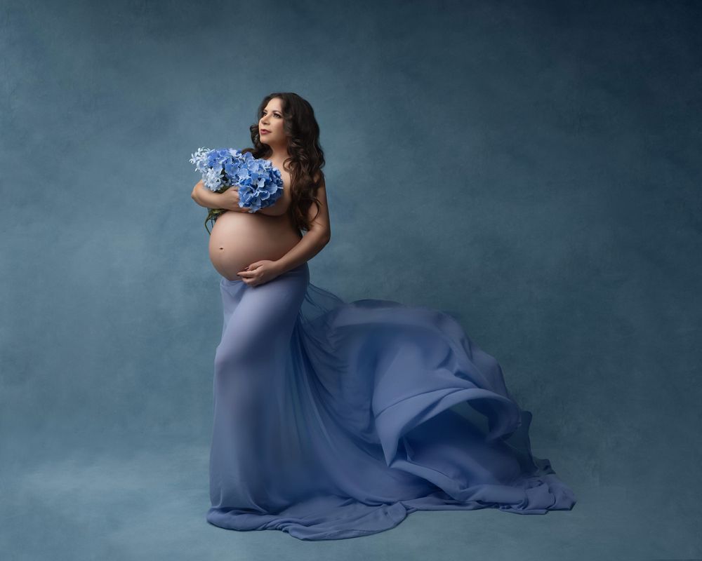 Artistic maternity portraits featuring flowing periwinkle fabric in studio setting.