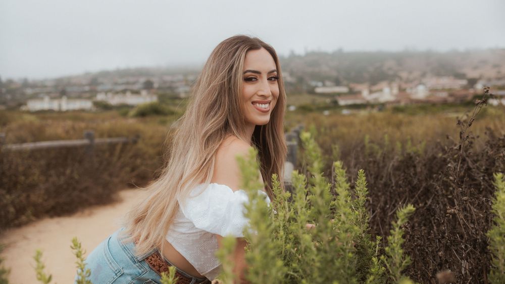 Casual outdoor portrait among wild plants with white top and natural scenery.