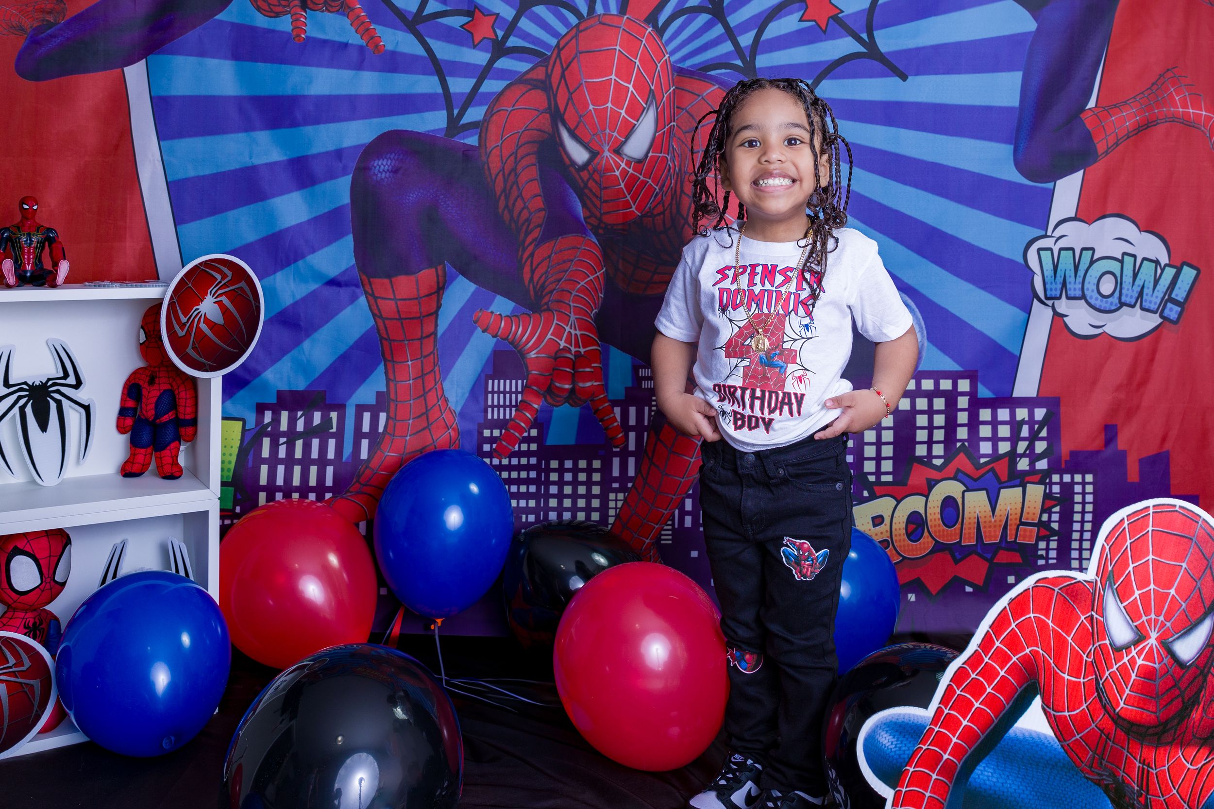 Spider-Man themed birthday party backdrop with red and blue balloons and cityscape decorations.