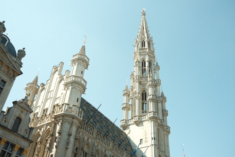 Gothic spires and ornate architecture of Brussels Town Hall against blue sky.