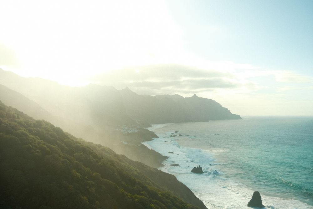 Misty coastal landscape with dramatic cliffs and ocean waves during golden hour.