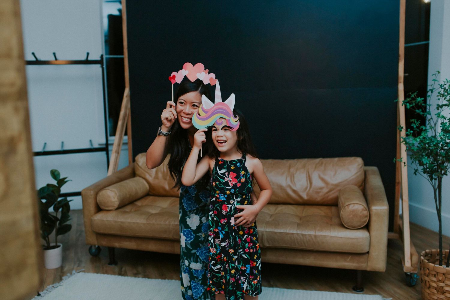 Family members share joyful moments in a studio setting with a dark blue wall and tan couch.