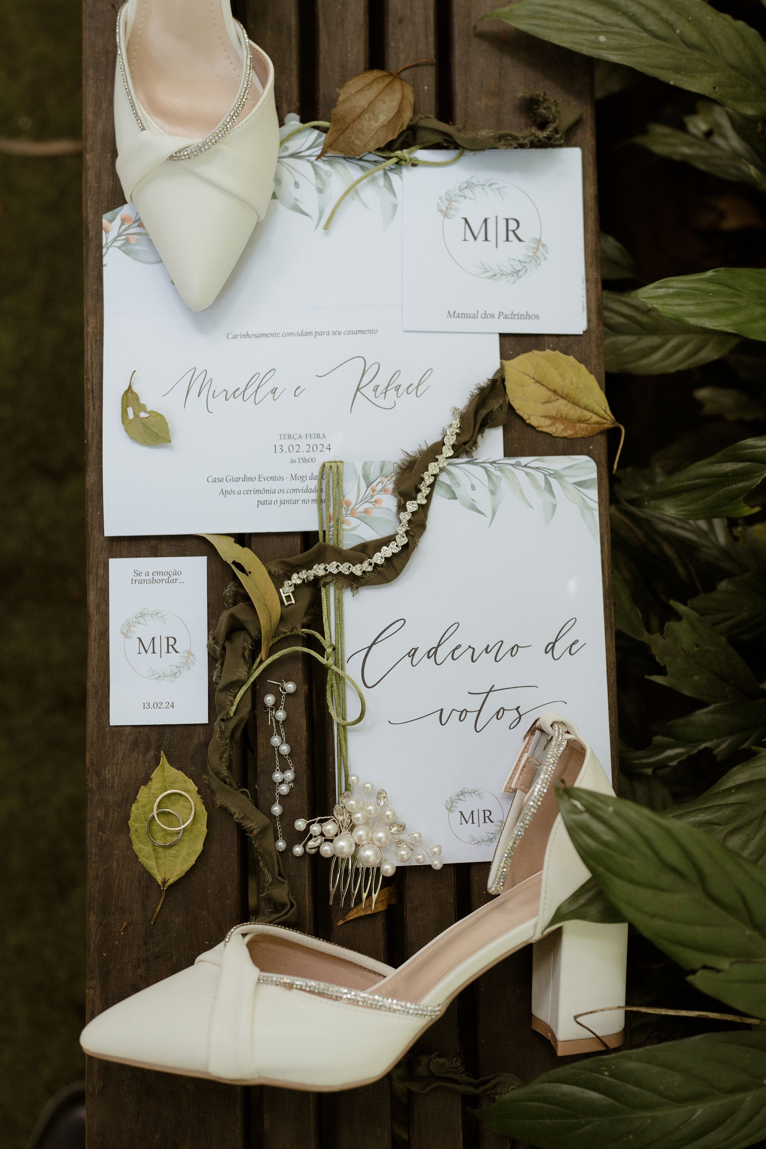Wedding invitation suite with elegant calligraphy and white heels against tropical foliage.