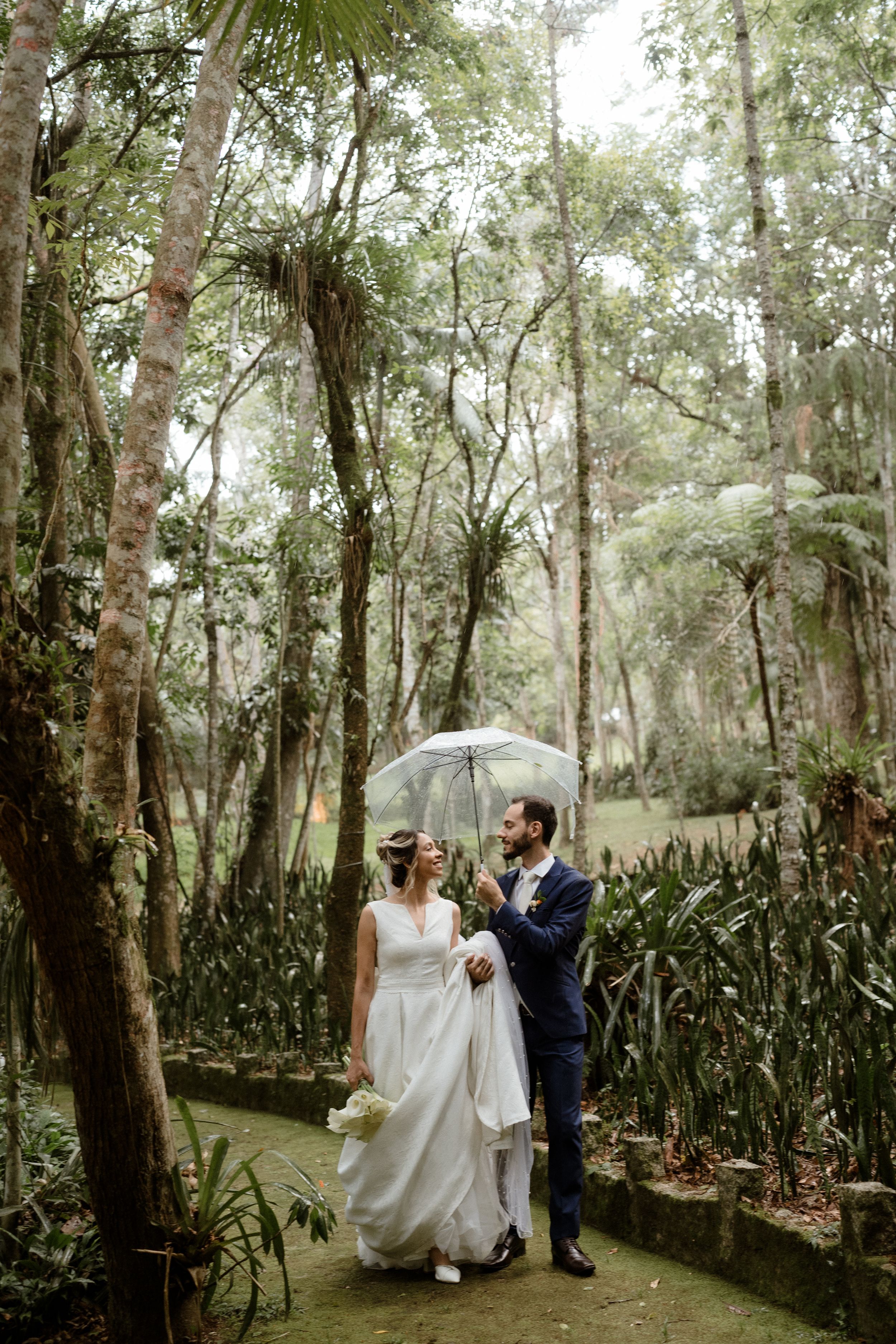 A couple shares intimate moments in a lush garden setting surrounded by tropical plants and trees.
