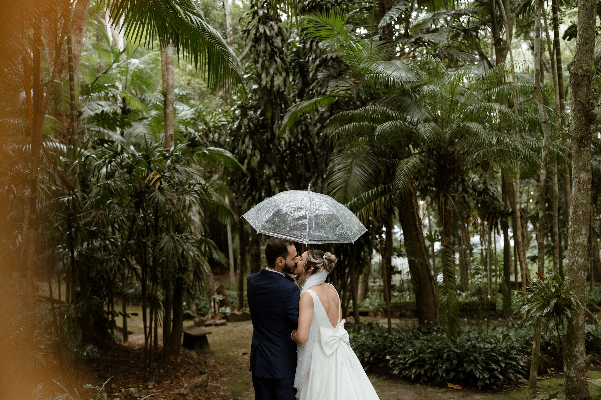 A couple shares a tender moment in a lush, green rainforest setting during their wedding.