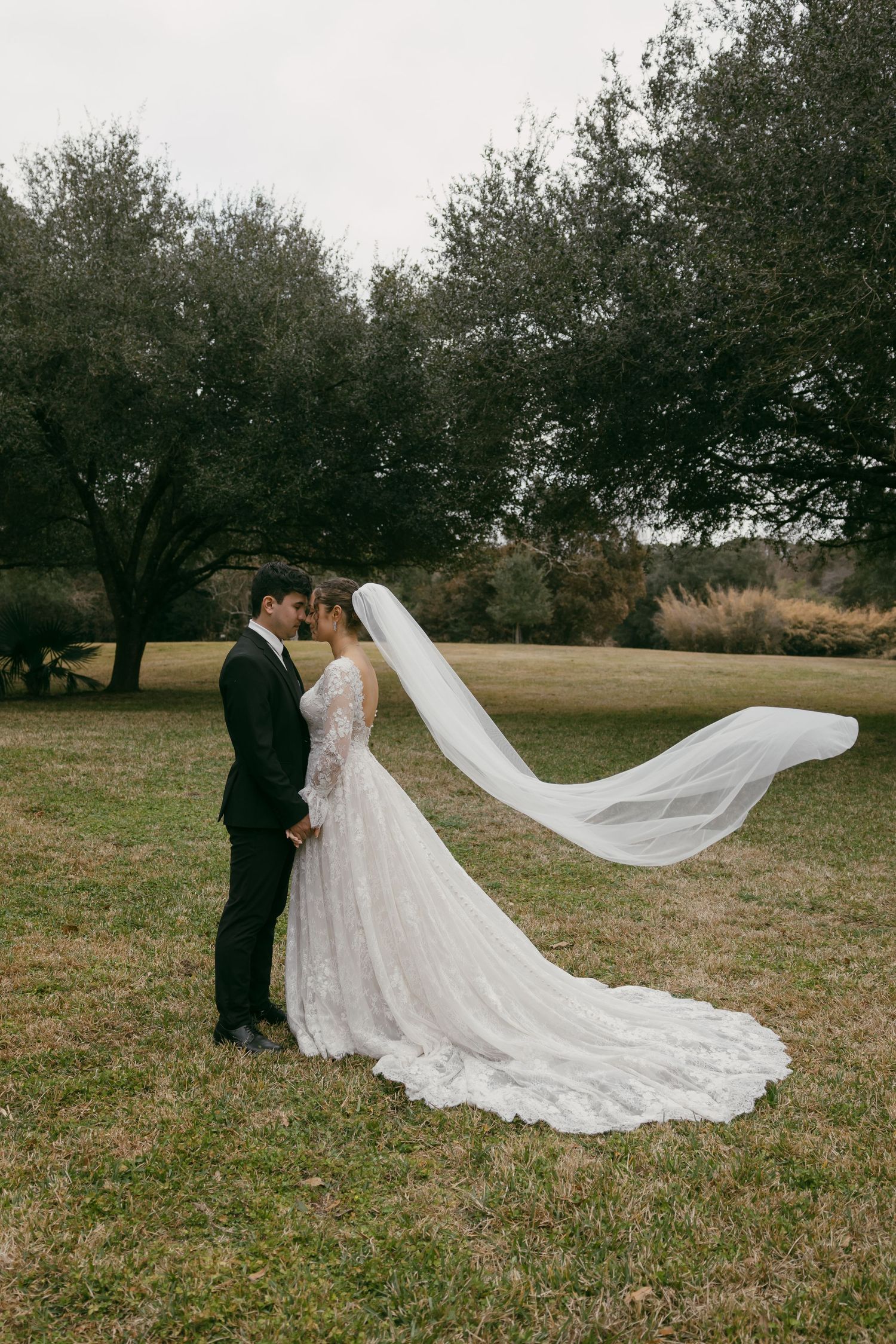 Black and white wedding photo showing a tender moment between a couple in formal attire.