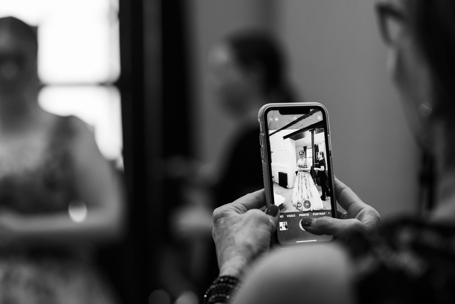 Close-up black and white shot of someone recording on a smartphone at an event.