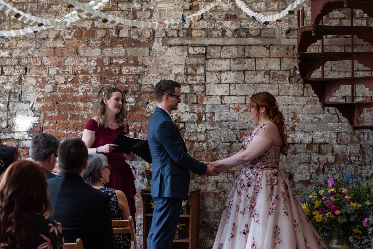 A rustic brick venue decorated with white streamers and floral arrangements.