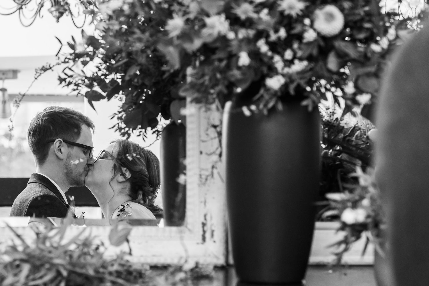 Black and white reception scene with decorative floral arrangements in vases.