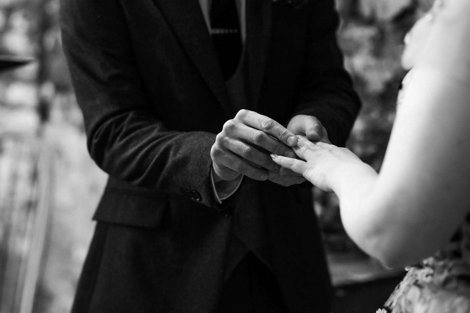 Wedding ceremony detail shot with focus on rings and hands.