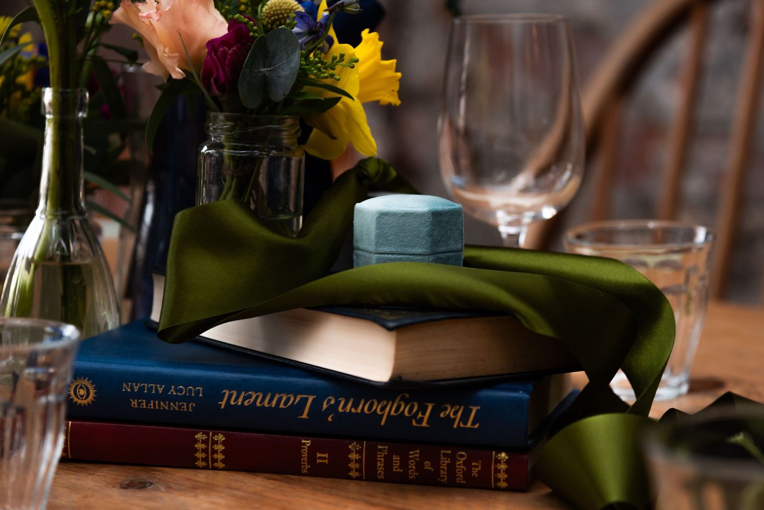 Table setting with floral arrangements and books visible in warm lighting.