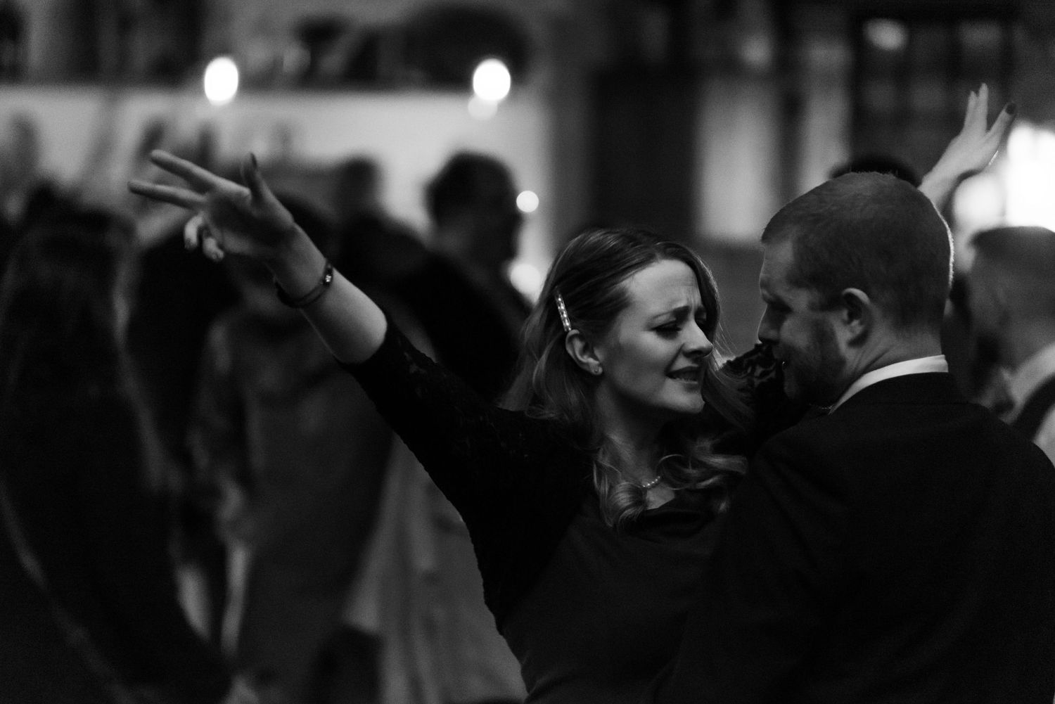 Wedding guests dance and celebrate on a dimly lit dance floor.