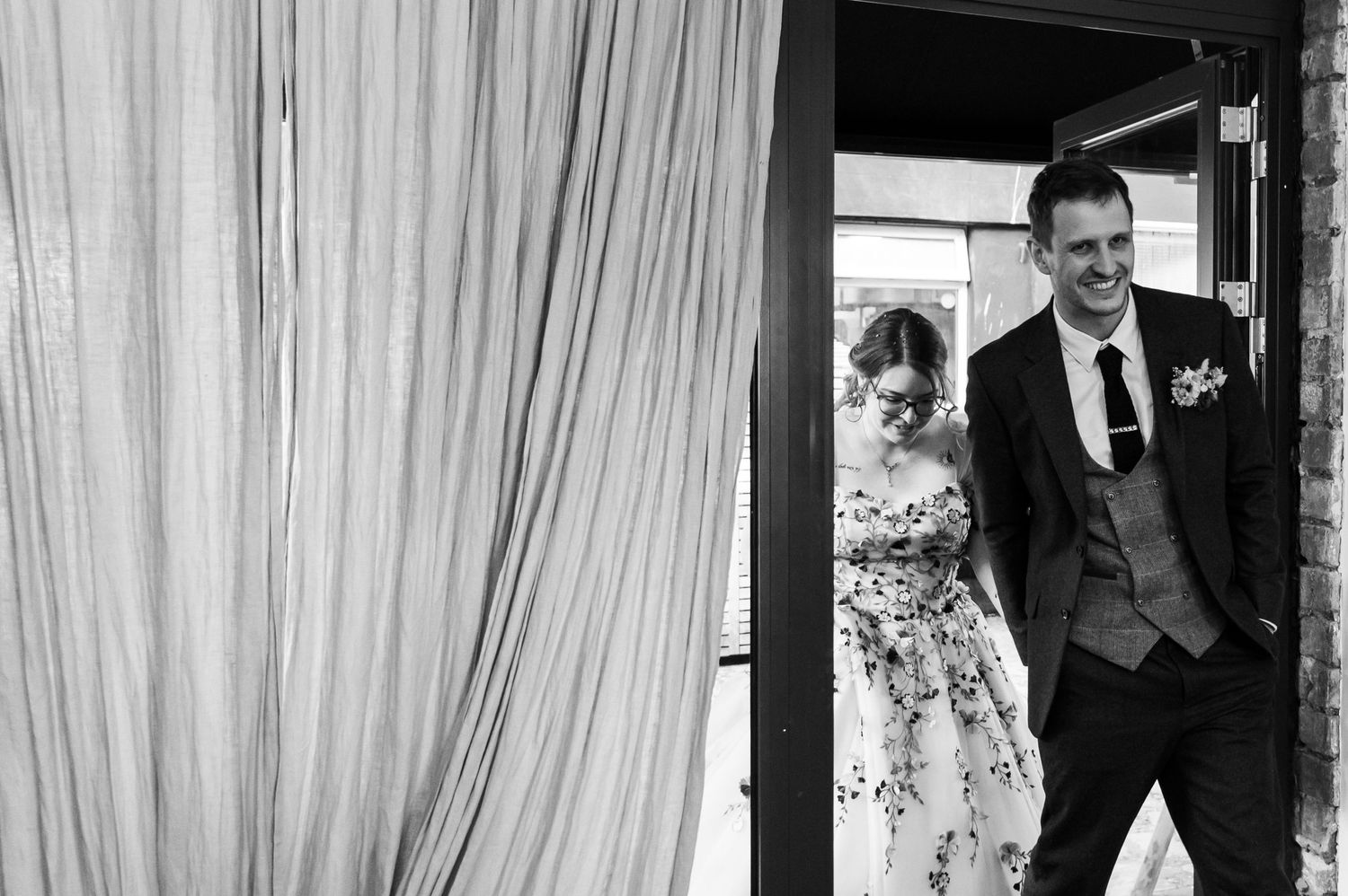 A couple shares a romantic moment in front of white curtains during their wedding photoshoot.