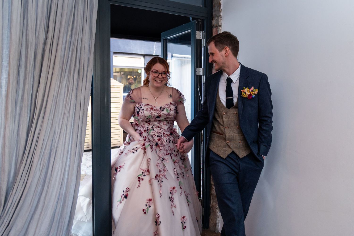 A wedding couple poses together against a light background in elegant attire.
