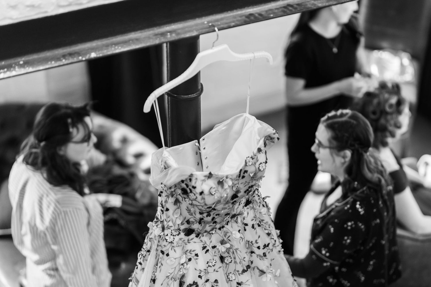 Black and white image of wedding dresses hanging on display.