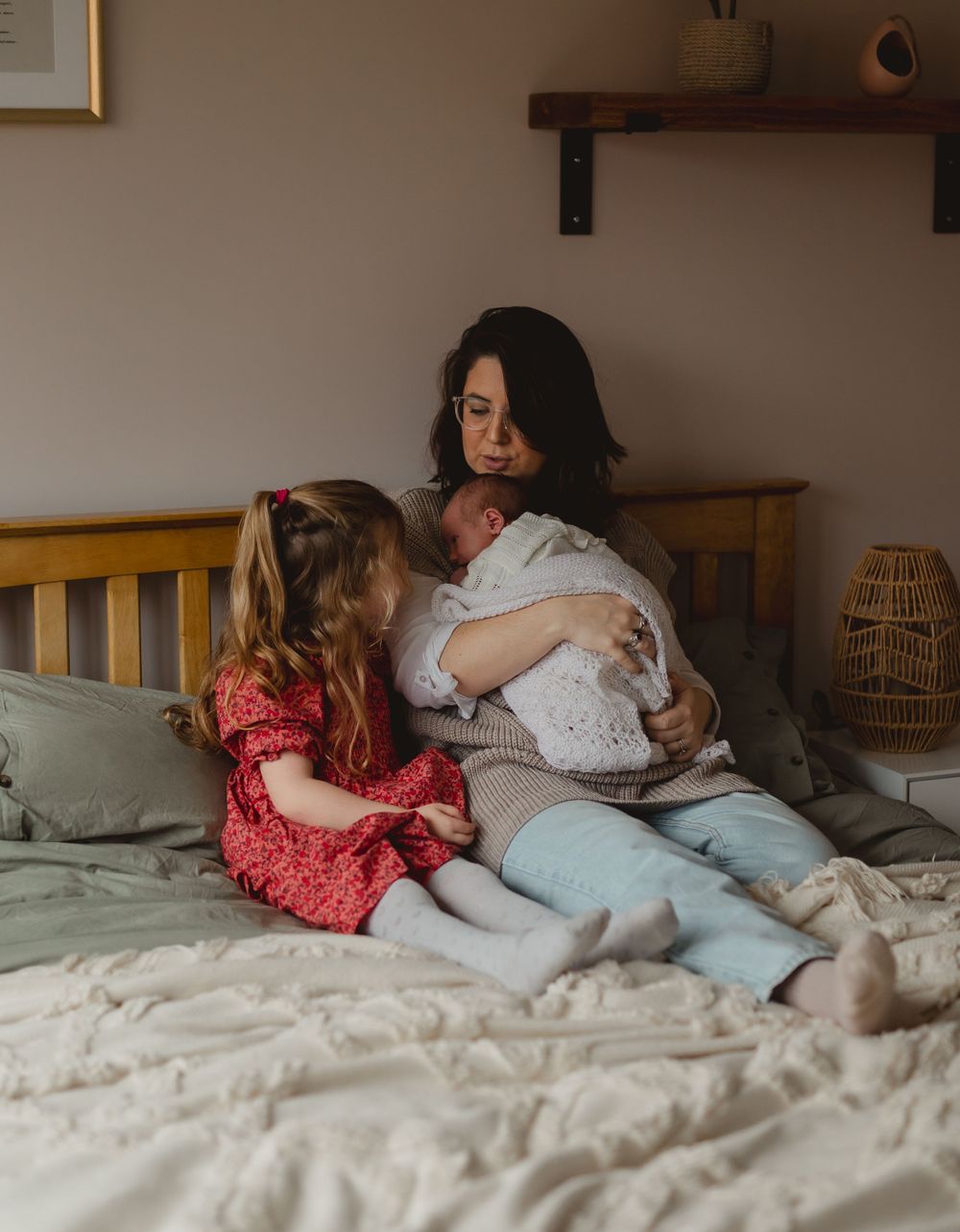 Cozy family moment captured on white bed linens in warm indoor lighting.