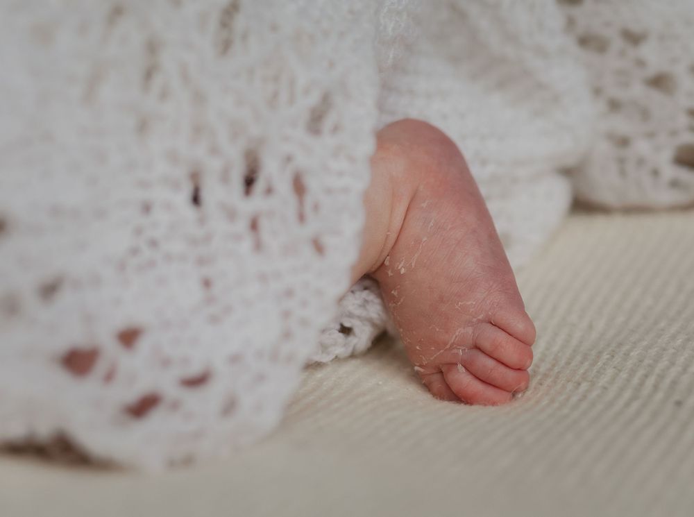 Close-up of hands untucking and smoothing bedding sheets across a mattress surface.
