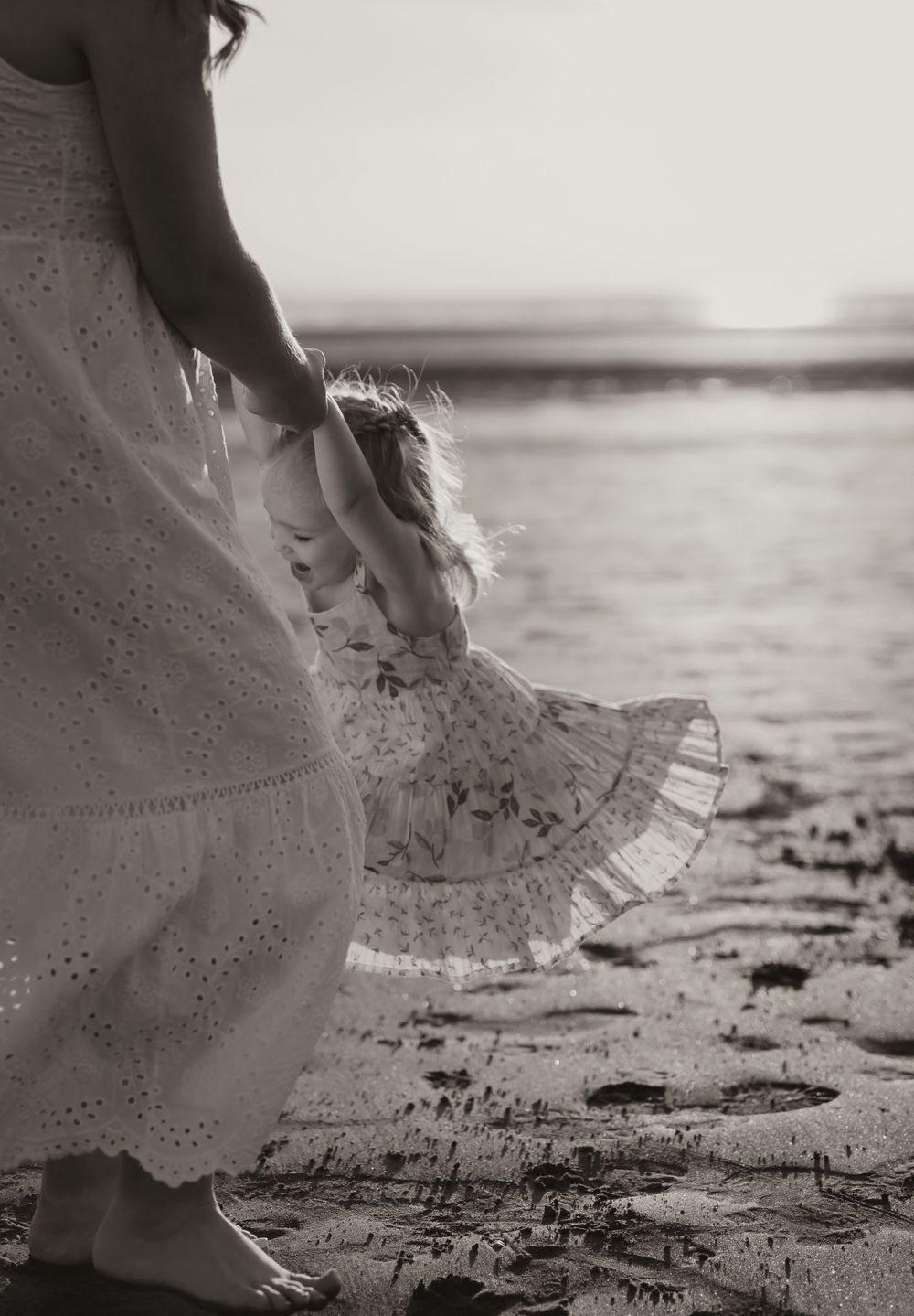 Ethereal black and white photo of dress hem swaying at beach shore.