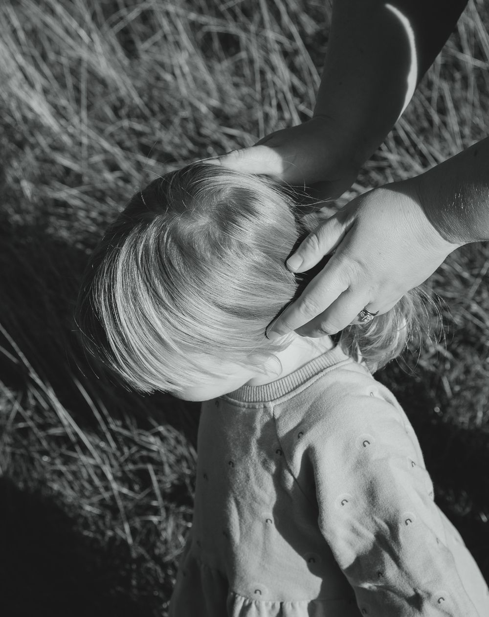 A series of black and white photos showing someone lying in tall grass with sunlight creating dramatic shadows.