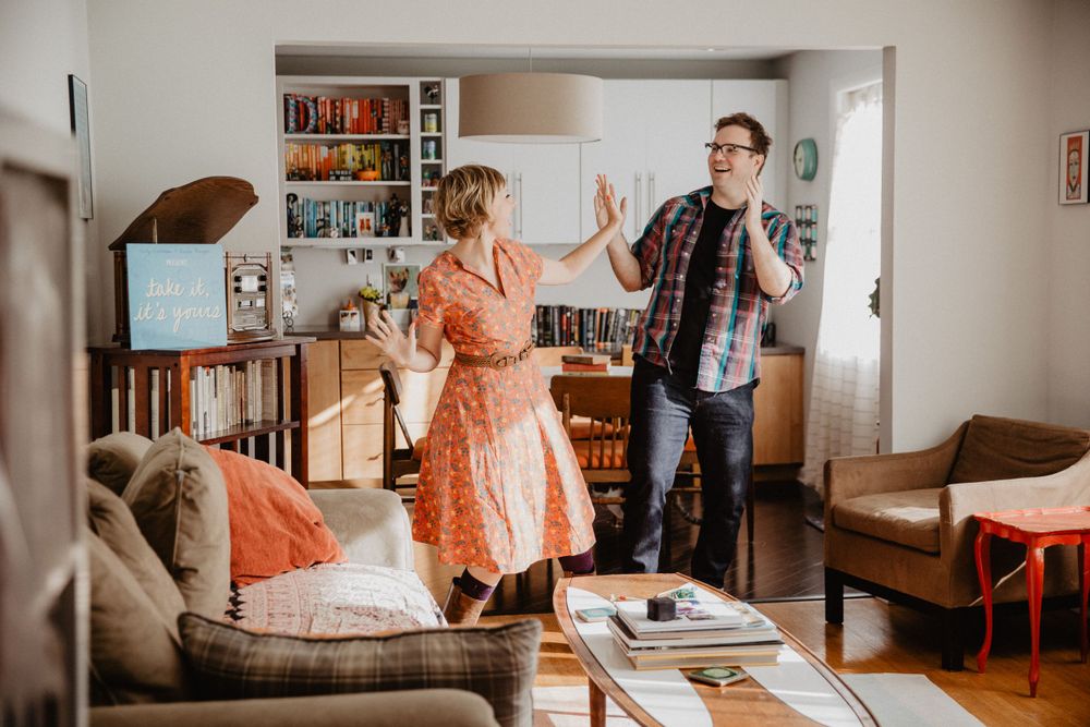 Dancing and celebrating in a cozy home living room with bookshelves.