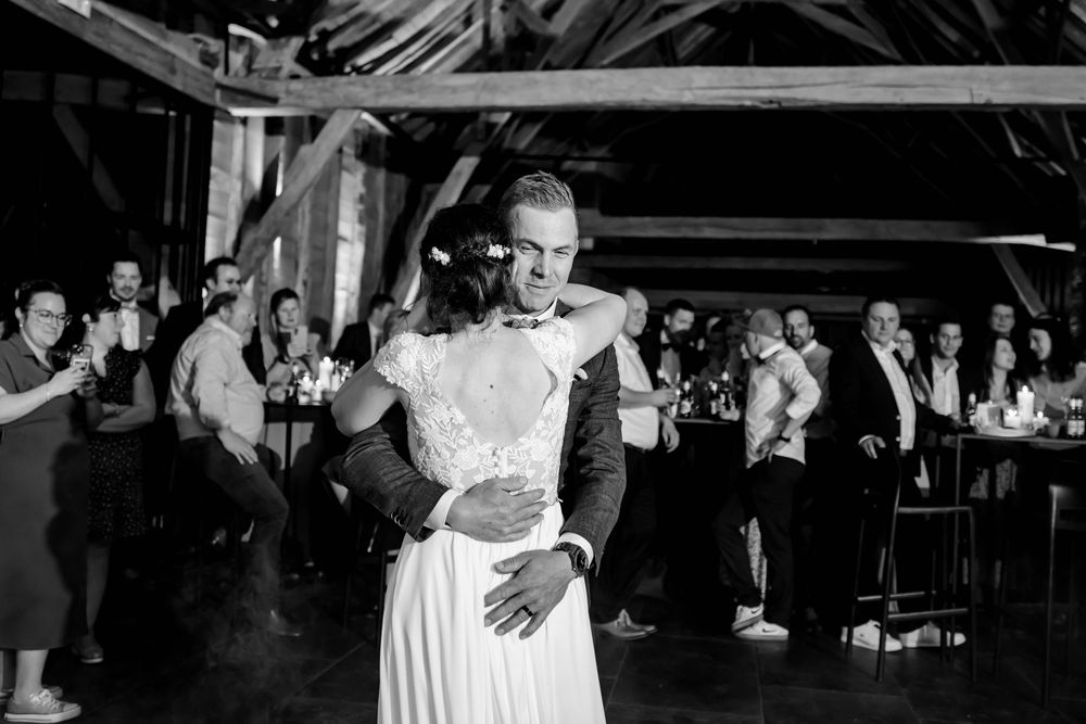 Black and white photo of a couple sharing their first dance at a wedding reception in a rustic barn venue.