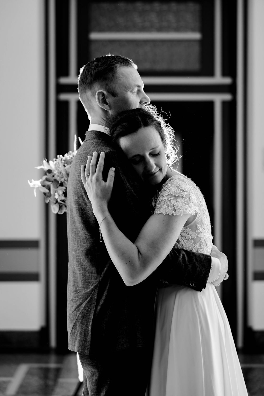 Black and white photo of a bride and groom sharing a tender embrace on their wedding day.