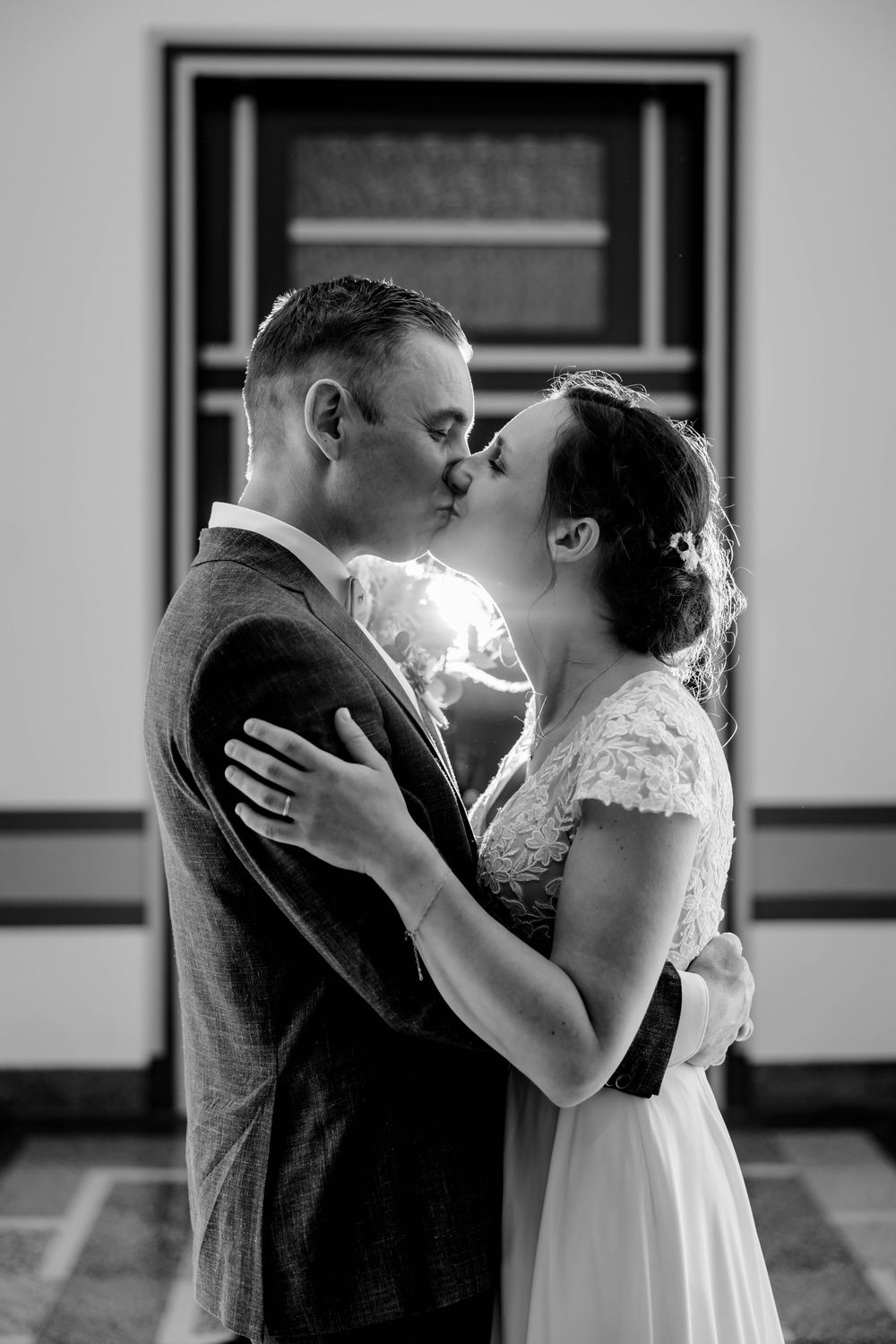 Black and white close-up of bride and groom sharing a romantic kiss outdoors on their wedding day.