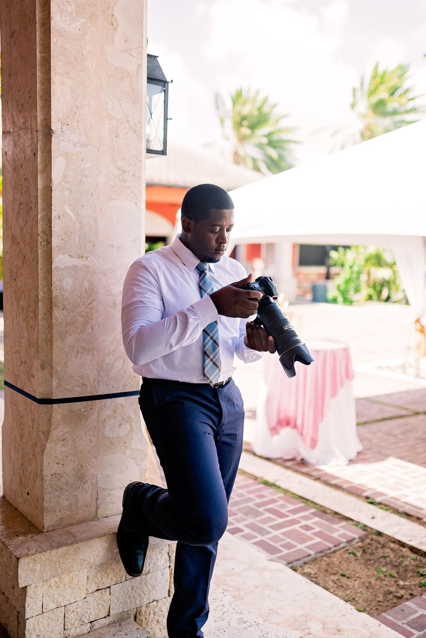 Professional photographer checking camera settings at outdoor event venue.