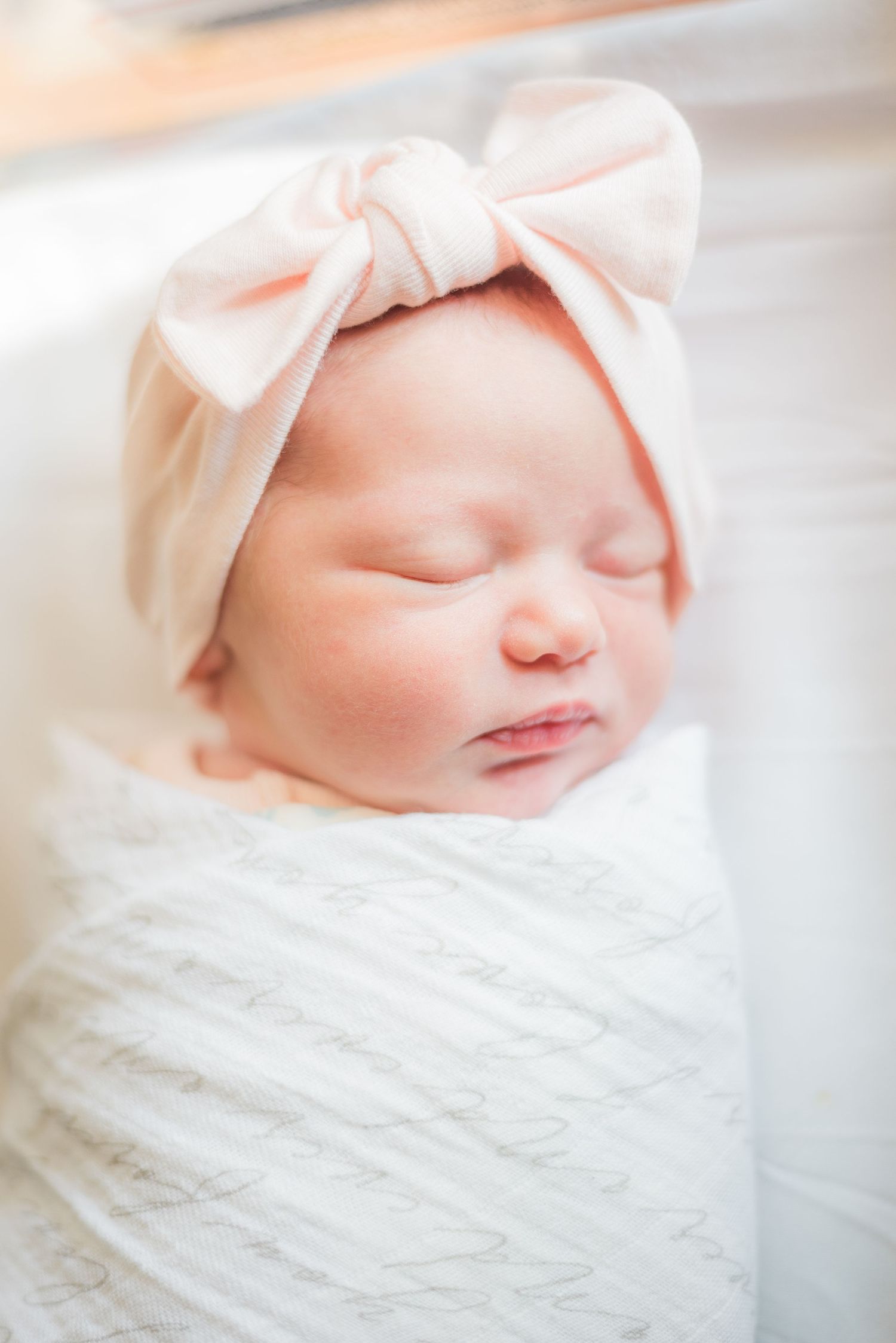 An up close portrait of a newborn girl swaddled and sleeping.