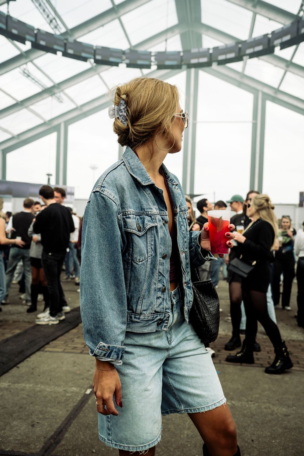 Person in denim jacket dancing at an indoor party with glass ceiling.