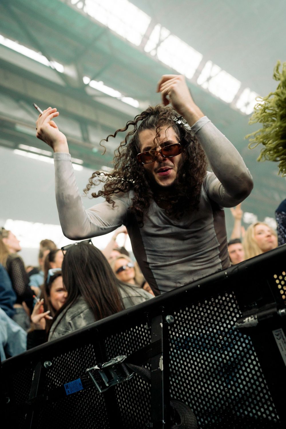 Person dancing energetically against safety barrier at indoor music event.
