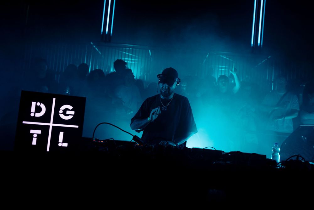 Silhouetted stage setup with blue neon lighting at an electronic music festival.