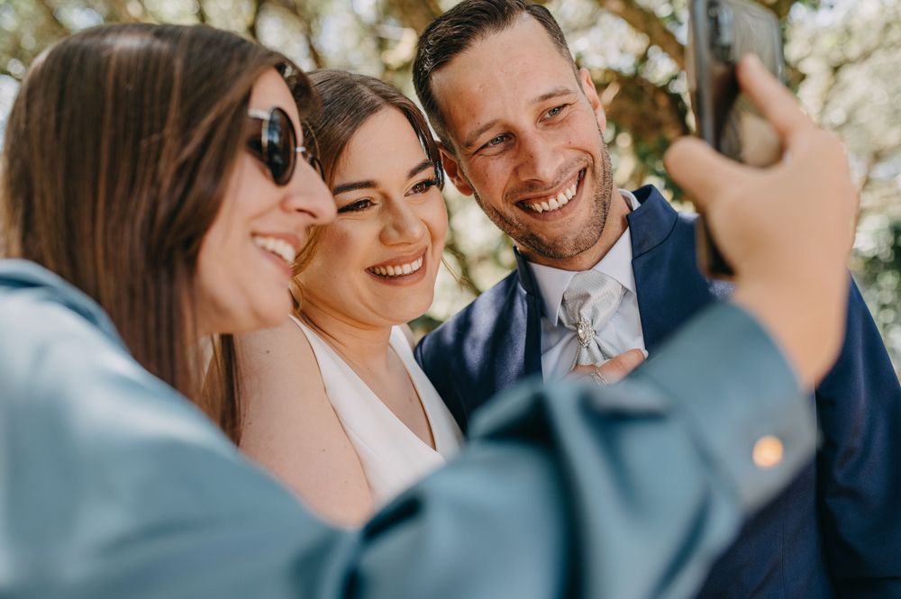 Group taking selfie photo together at outdoor celebration.