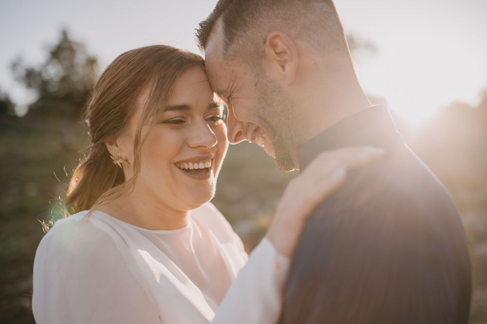 An intimate moment between a couple sharing laughter during their wedding photoshoot at sunset.