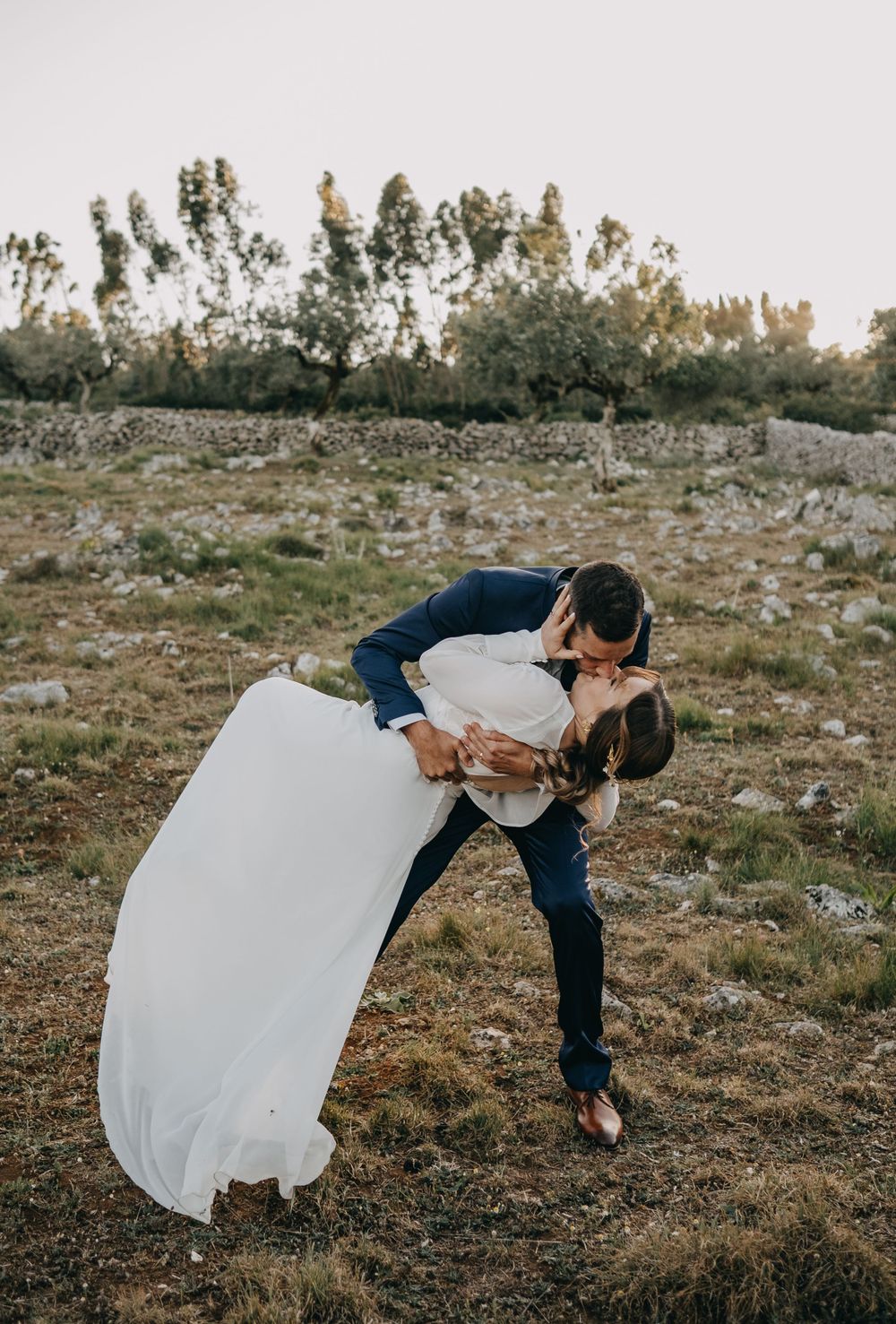 A romantic dip pose between newlyweds on a rocky outdoor setting.