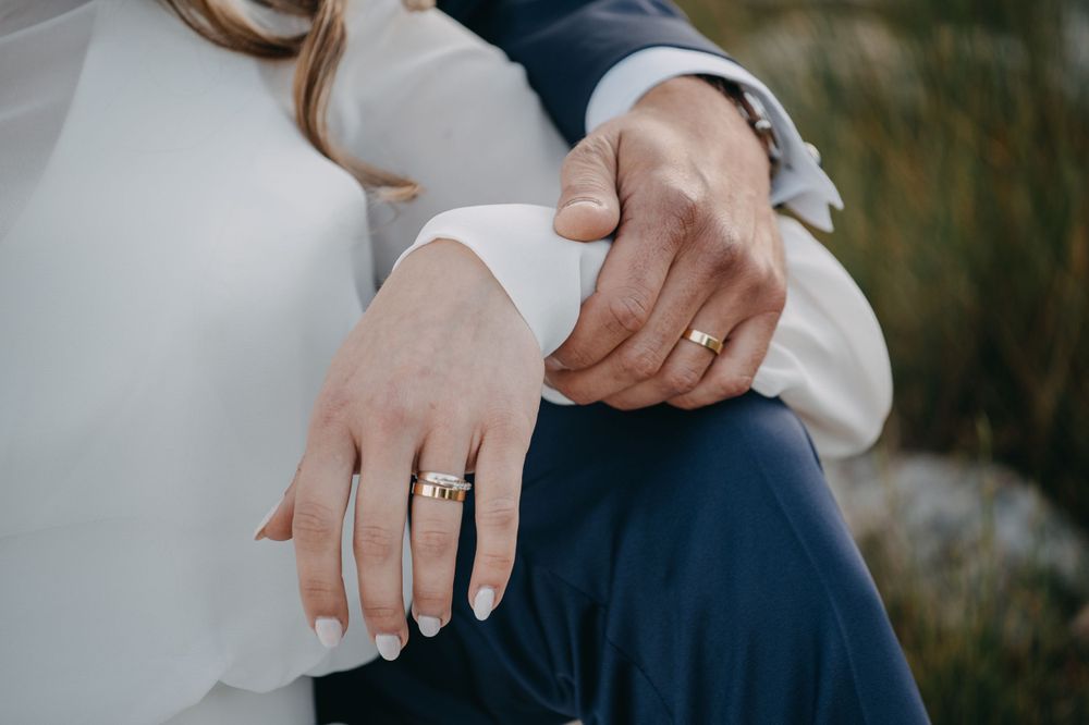 Close-up of wedding rings and joined hands showing elegant wedding day jewelry.
