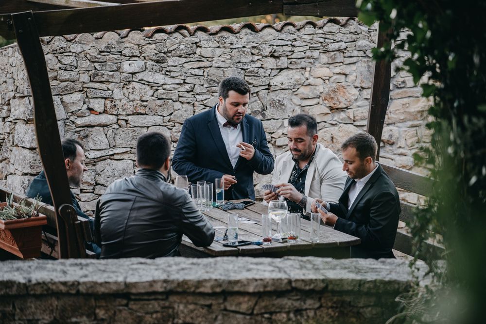 A group of men playing cards at a stone table outdoors.
