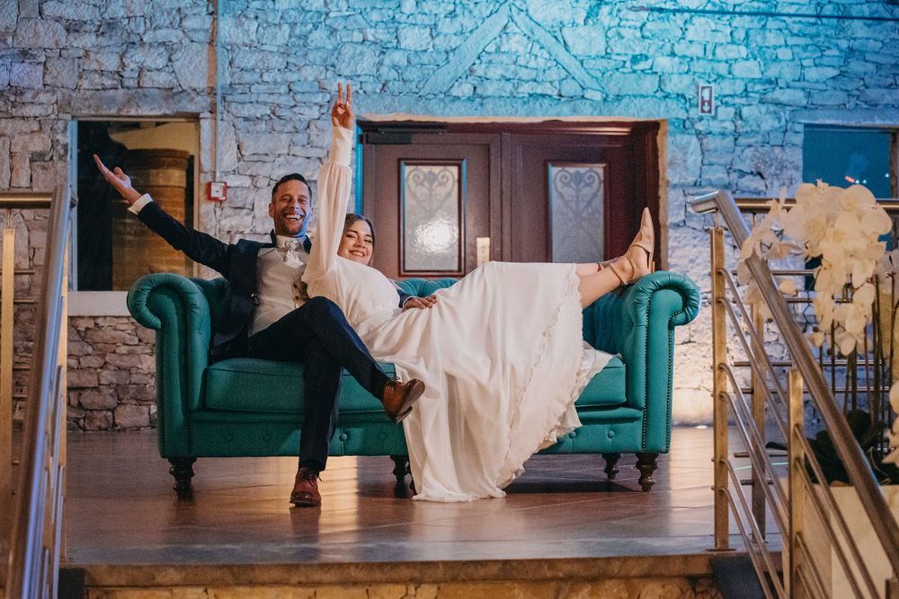 Joyful moment on a teal velvet couch in a rustic stone venue.