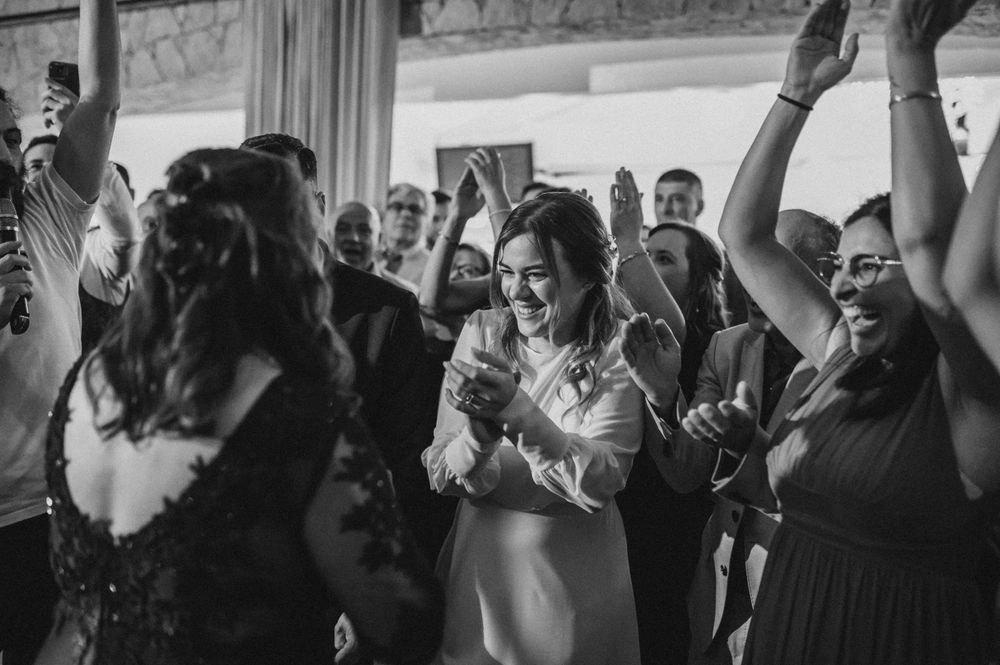 Joyful celebration with people dancing and raising their hands in a black and white photo.