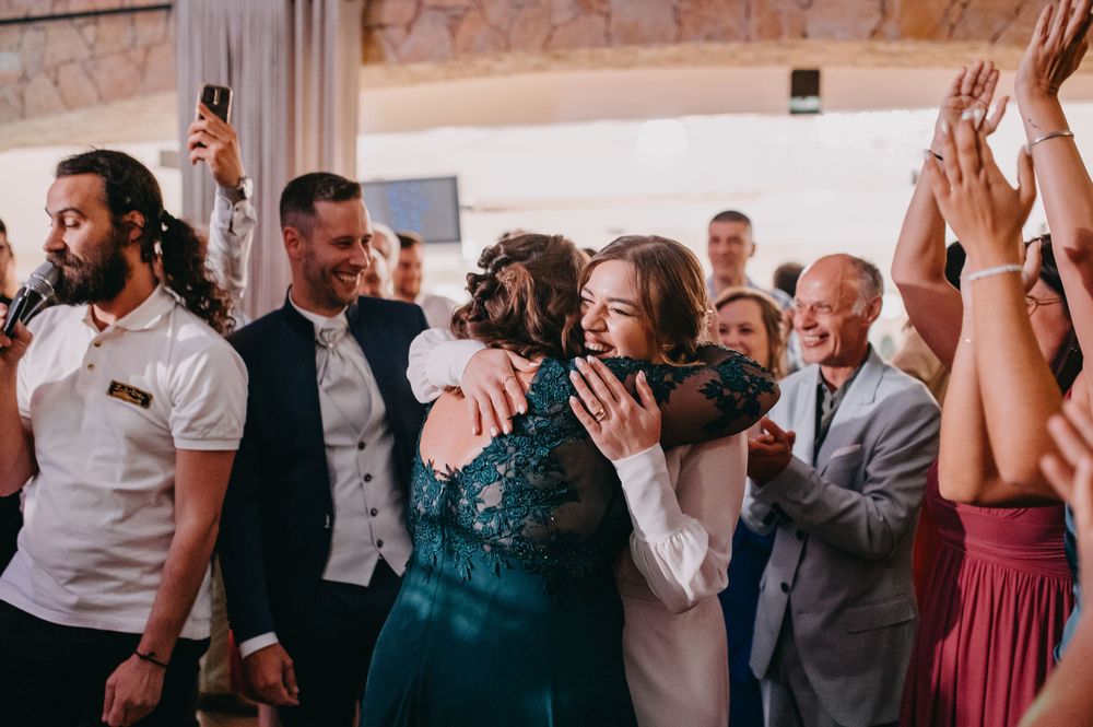 Guests celebrate emotionally during a wedding reception in a stone-walled venue.