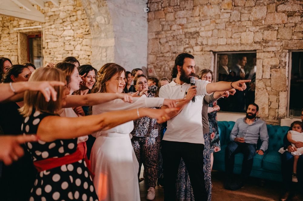 Wedding party performs synchronized dance moves in a rustic stone venue.