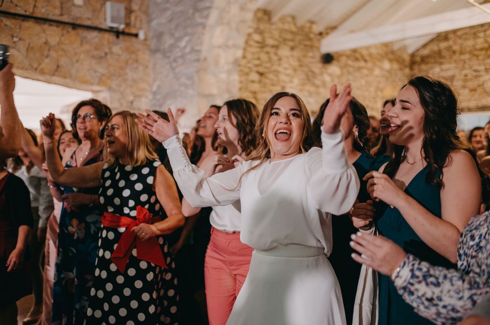 Enthusiastic dancers raise their arms while celebrating at a wedding reception.